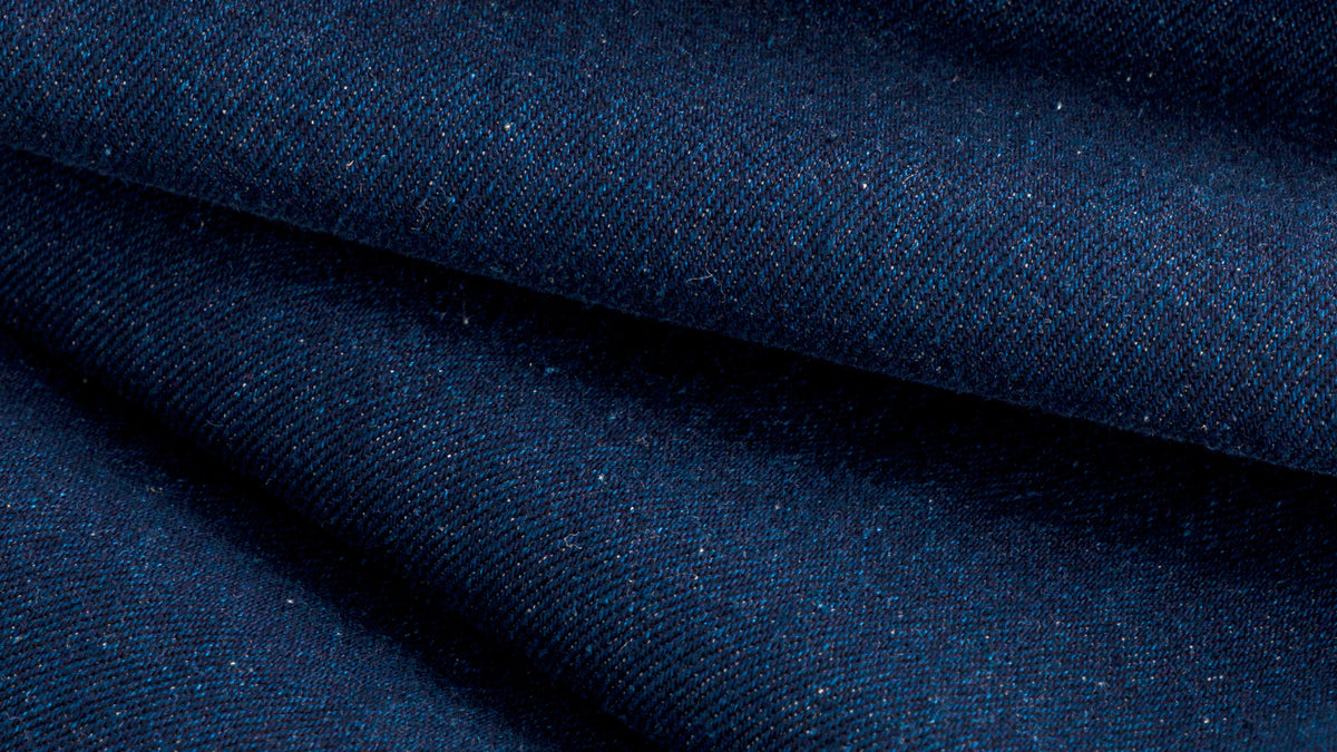 Tissu denim bleu indigo texturé en vue paysage montrant le tissage sergé détaillé.
